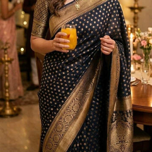 Person wearing a blue saree with gold patterns, holding a glass of orange juice.