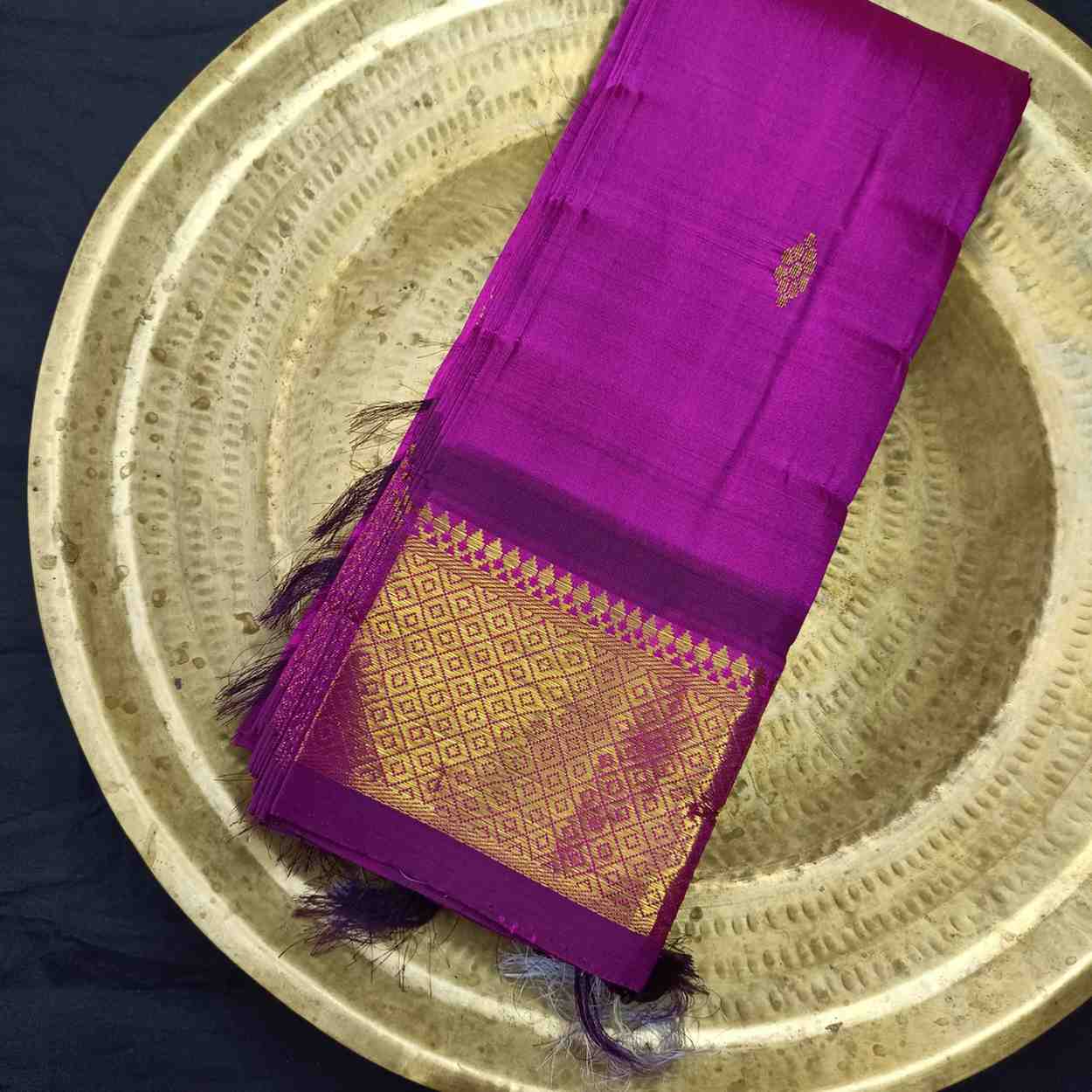 Purple saree with gold border on a metallic tray