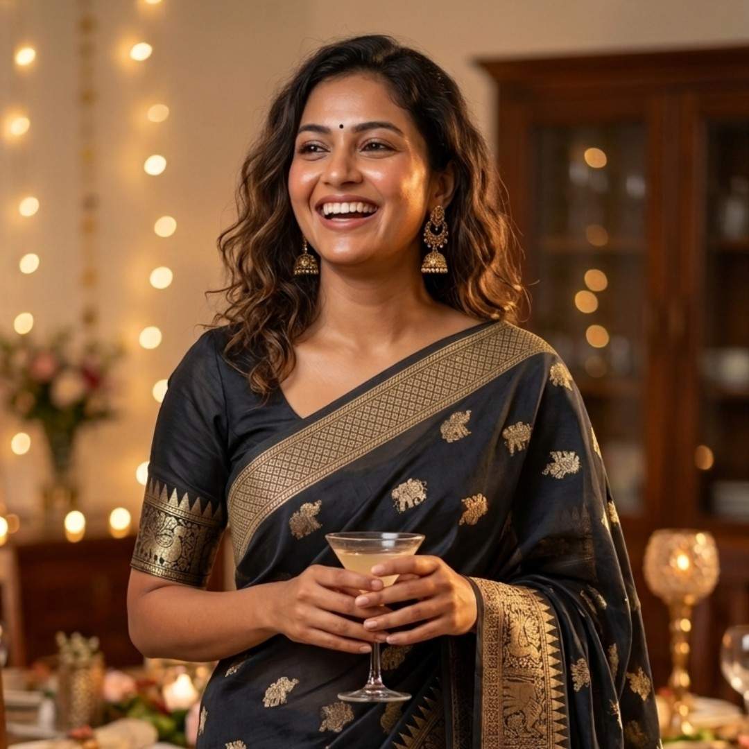 Woman in traditional attire holding a glass in a festive setting with string lights.