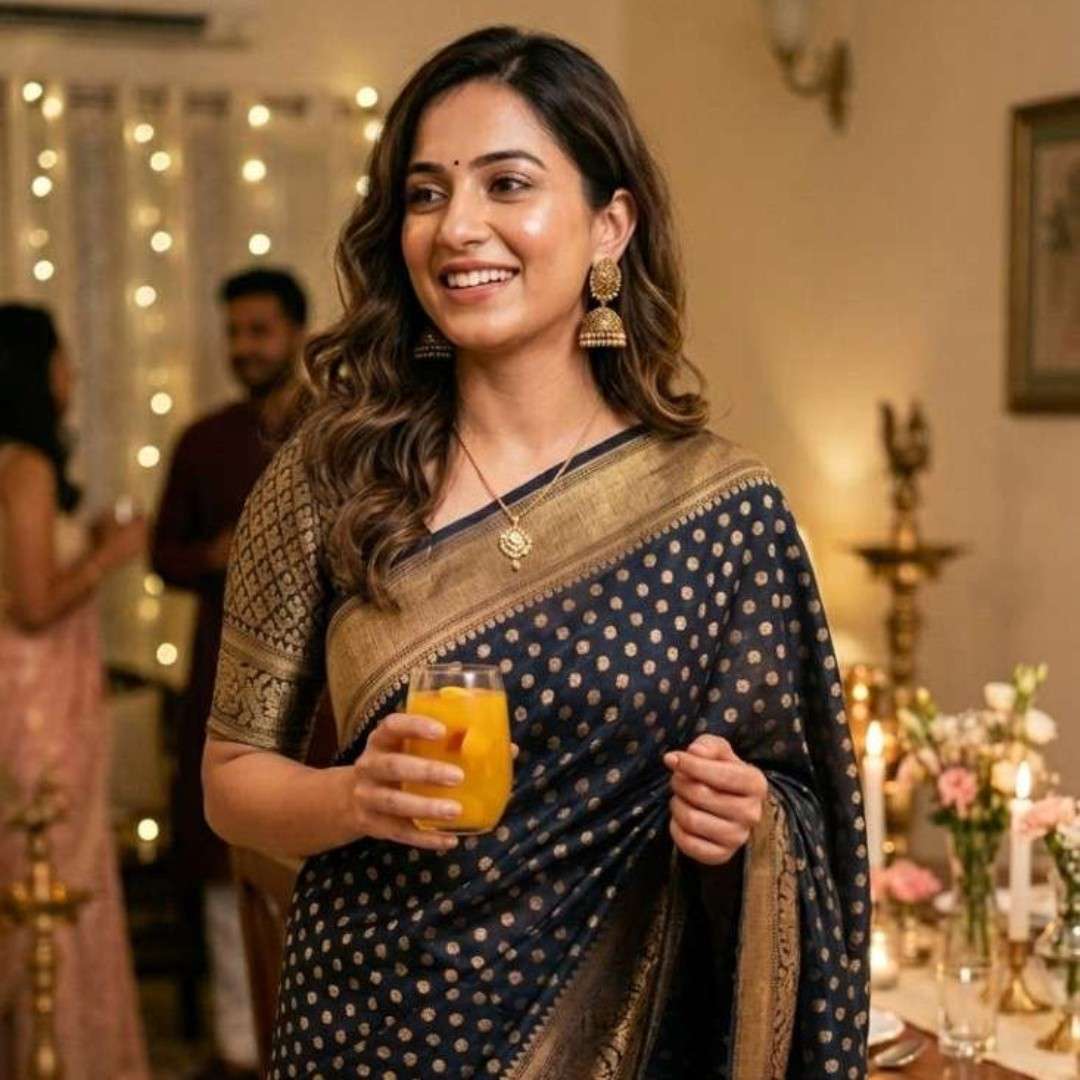 Woman in traditional attire holding a glass of orange juice in a festive indoor setting.