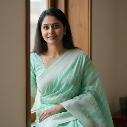 Woman in a light green saree sitting by a window
