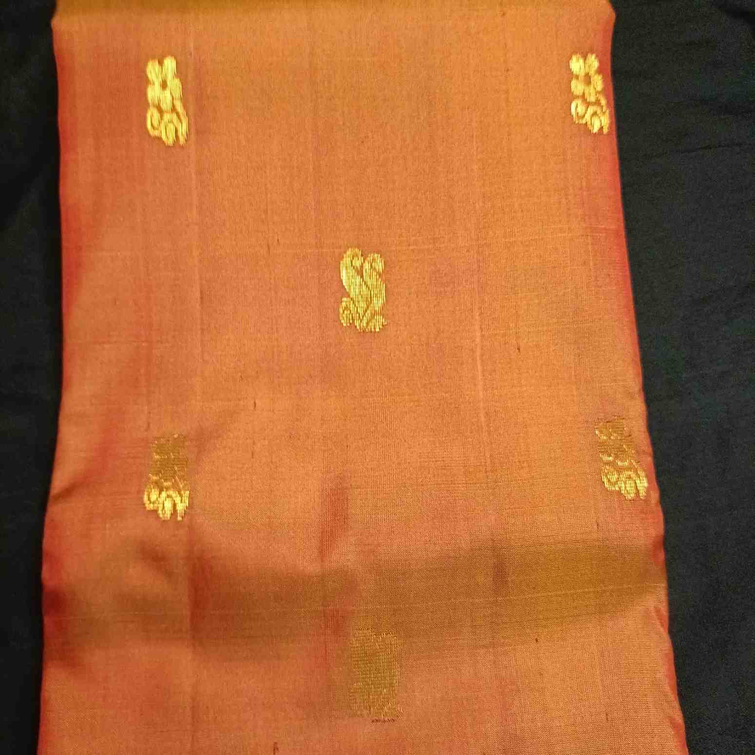Poo flower motifs with Rettai Mayil peacock forms on earthy orange Kanjivaram silk