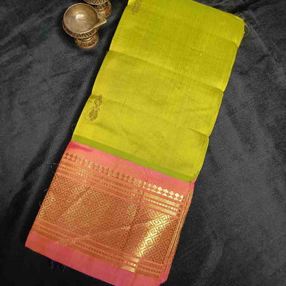 Close-up of orange-pink Mayil Kan peacock eye zari border on parrot green Thirubhuvanam saree