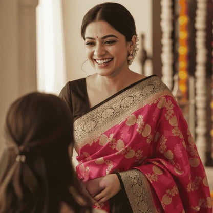 Woman in a pink saree with gold patterns smiling indoors