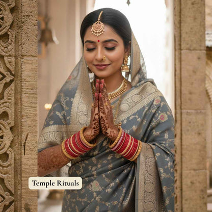 Woman in traditional attire with jewelry and henna, standing in a temple setting.
